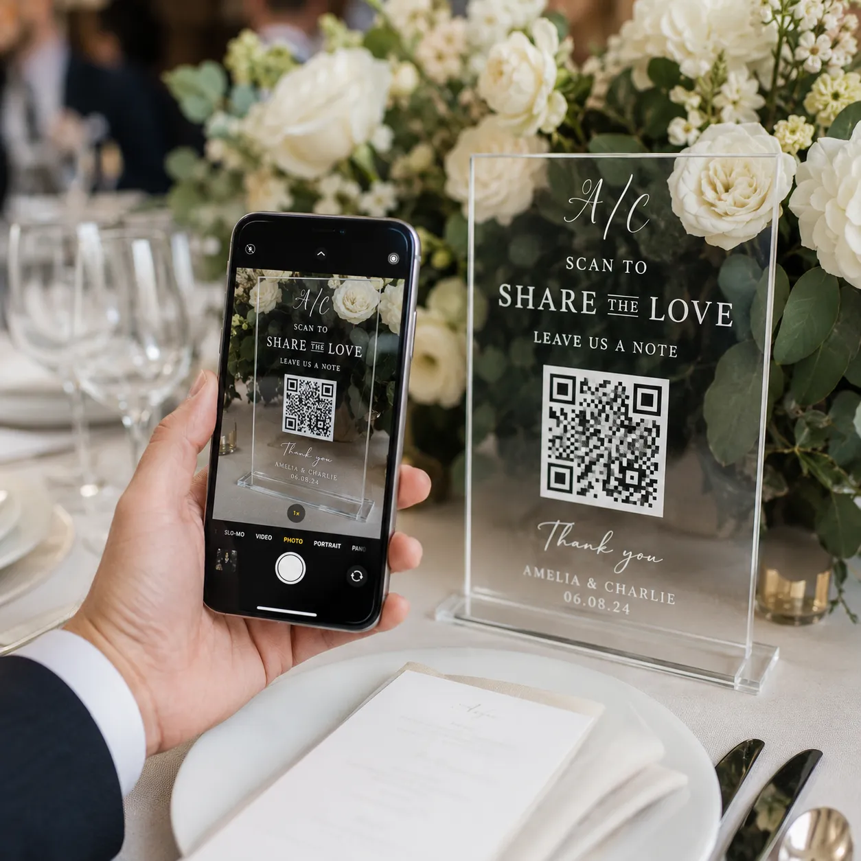 Close-up of a guest using a smartphone to scan a QR code on an elegant acrylic wedding table sign.